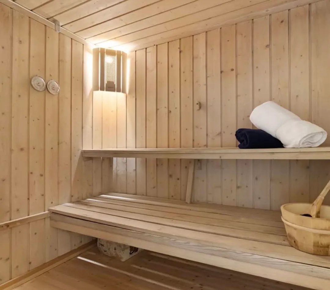 Wooden sauna interior with folded towels and a wooden bucket
