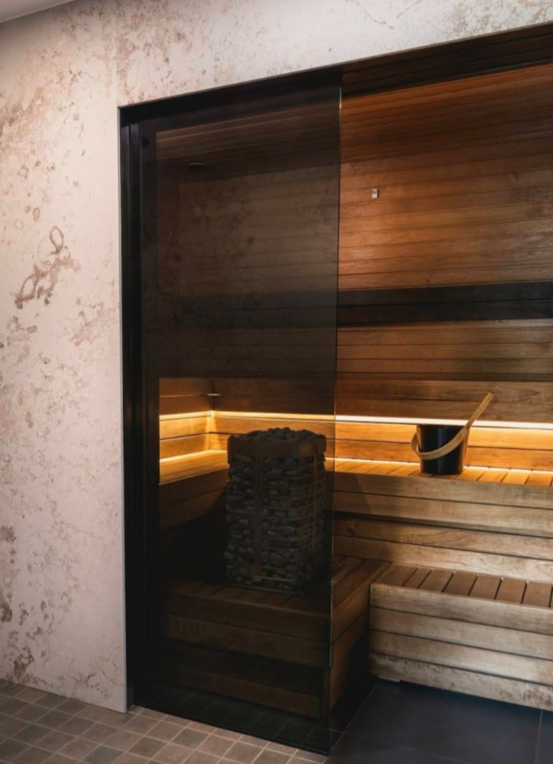 Sauna Zone at The Moment Massage Athens Natural wood sauna zone with benches, sauna stones, bucket and warm lighting