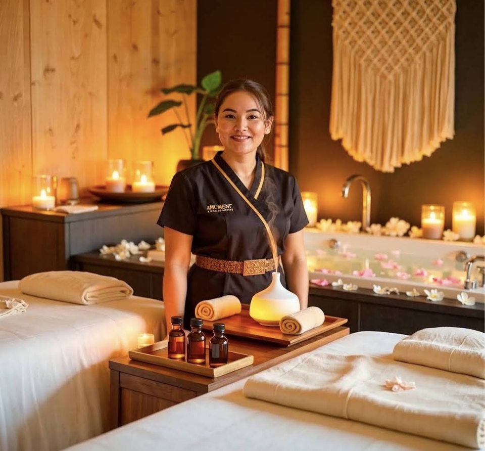 Massage professional between two prepared tables in a warmly lit room with a bathtub