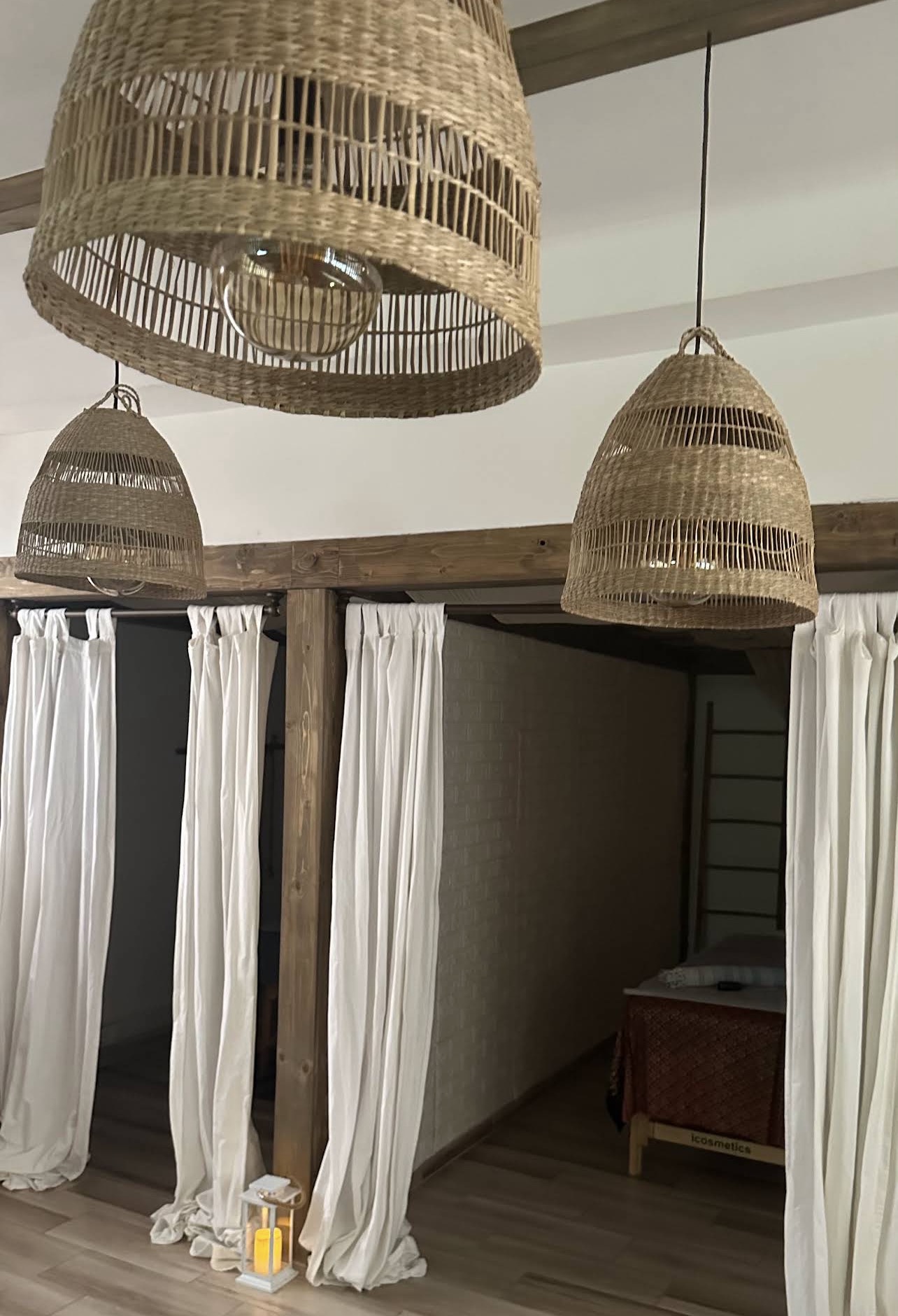 Curtained private massage bays beneath woven pendant lights at The Moment