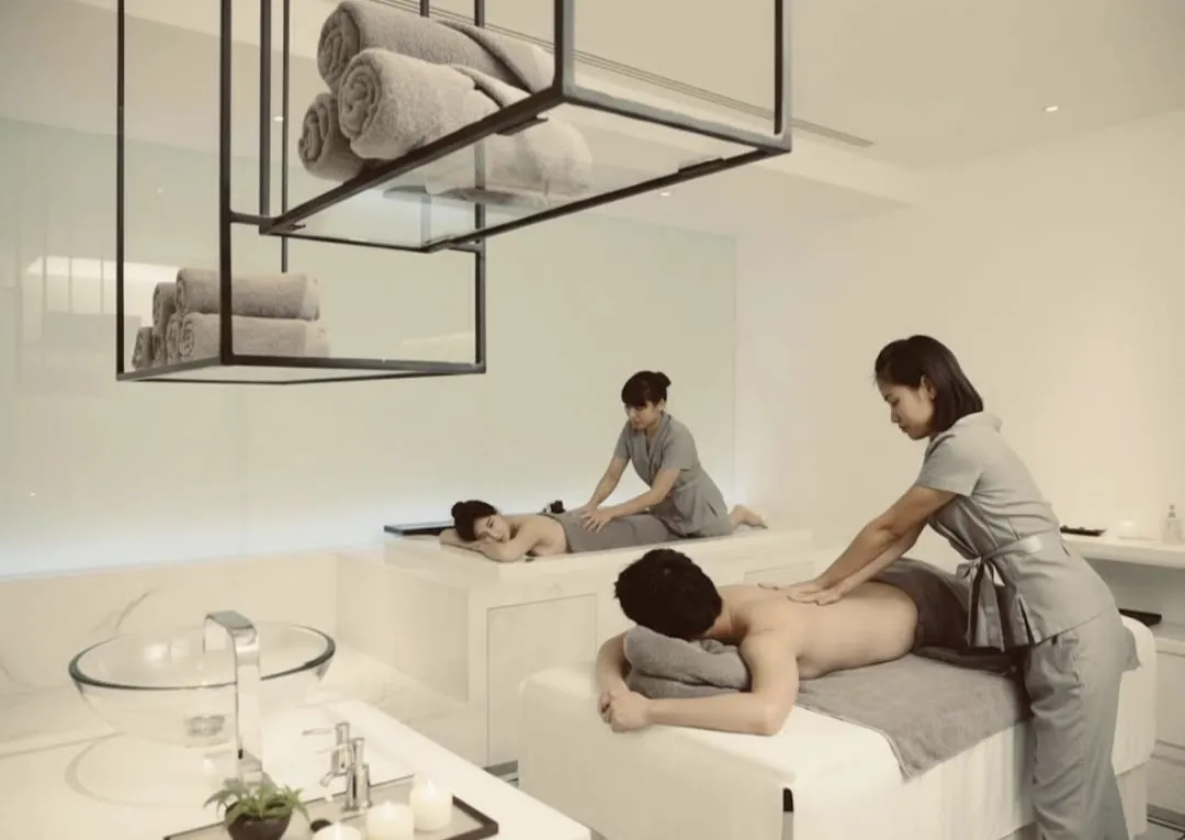 Two guests receiving massage on separate tables in a bright treatment room